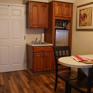 A cozy kitchenette with wooden cabinets, a round dining table, and hardwood flooring.
