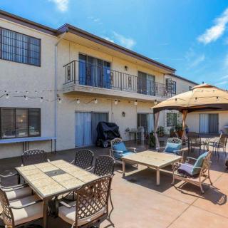 A spacious outdoor patio with tables, chairs, and an umbrella under a clear blue sky.