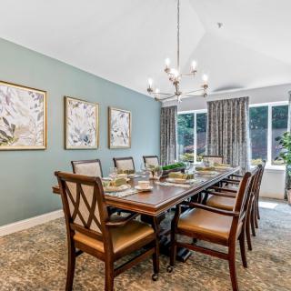 A well-decorated dining room featuring a large table with multiple chairs, a modern chandelier, and artwork on the walls.