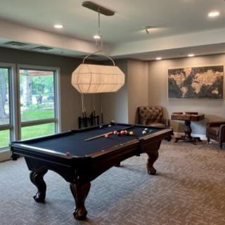 A modern billiard room featuring a pool table, comfortable seating, and elegant lighting.