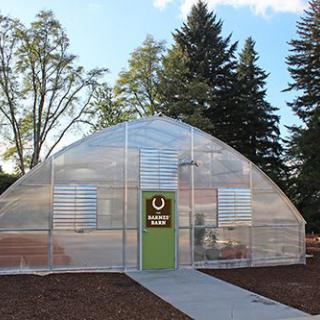 A modern greenhouse surrounded by trees.