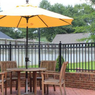 A cozy backyard patio with wooden furniture and a large yellow umbrella.