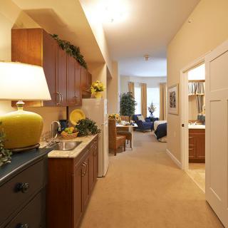 A cozy hallway leading to a living area, featuring warm lighting and wooden cabinetry.