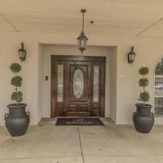 A symmetrical entrance with a wooden front door, flanked by potted plants and lanterns.