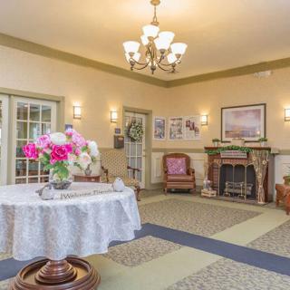A cozy lobby area with a chandelier, fireplace, and floral decorations.