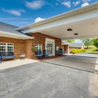 A building entrance with a covered driveway and brick exterior under a clear blue sky.