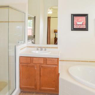 A modern bathroom with a glass shower, bathtub, and sink with wooden cabinet.