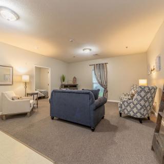 A cozy living room with a blue sofa, patterned armchair, and soft lighting.