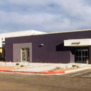 A modern commercial building with a parking area in front.