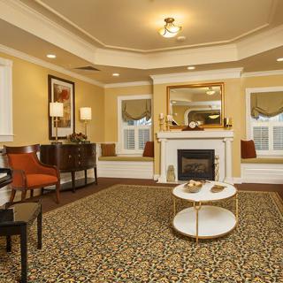 A cozy living room with a central fireplace, elegant furniture, and warm lighting.