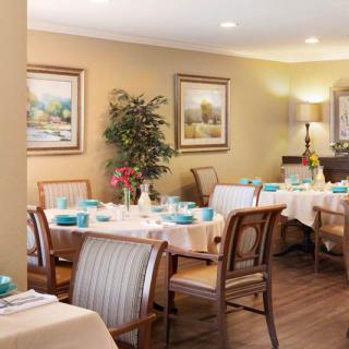 A cozy dining room with neatly arranged tables set for a meal, decorated with artwork and plants.