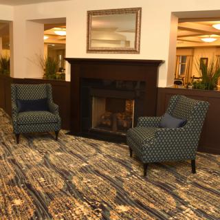 A cozy lounge area with two armchairs facing a fireplace, featuring a patterned carpet.