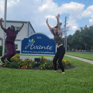 Two individuals joyfully jumping in front of the Avante sign.