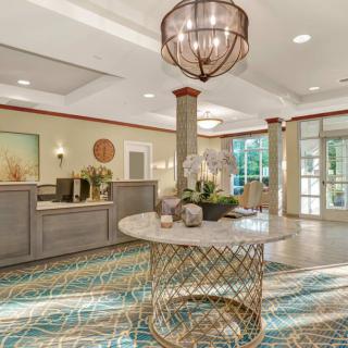 A modern and elegant lobby with a central table, featuring a chic chandelier and reception area.