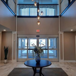 A modern lobby with a central round table, decorative plant, and chandelier lighting.