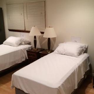 A bedroom with two twin beds and a shared nightstand, each bed adorned with clean white bedding and accompanied by table lamps.
