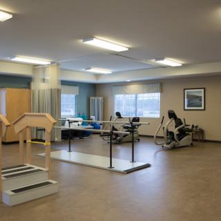 A spacious physical therapy room equipped with various exercises and rehabilitation tools.