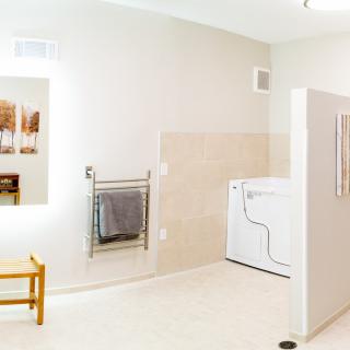 A spacious bathroom with a washer and dryer, featuring a mirror and towel rack.