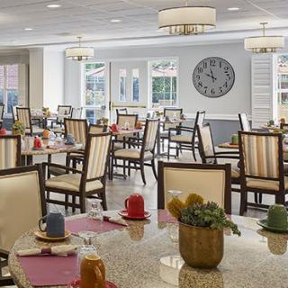 A bright and neatly arranged dining area with multiple tables and chairs, decorated with colorful table settings.