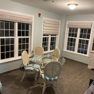 A cozy dining room with a glass table and upholstered chairs near large windows.