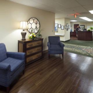 A cozy lobby area with blue chairs and wooden flooring.