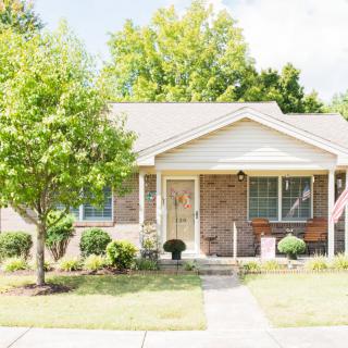 A suburban house with a well-maintained front yard featuring trees and shrubs.