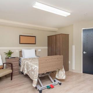 A simple hospital room featuring a bed and basic furniture.