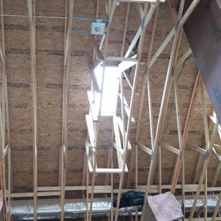 View of the interior roof structure highlighting wooden beams and natural light.