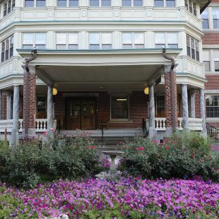 An ornate building entrance surrounded by a vibrant flower garden.