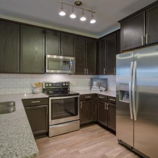 A modern kitchen featuring stainless steel appliances and dark cabinetry.