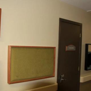 A hallway featuring a notice board mounted on beige walls, with a closed door nearby.