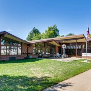 A mid-century modern house with a spacious lawn and outdoor patio area.