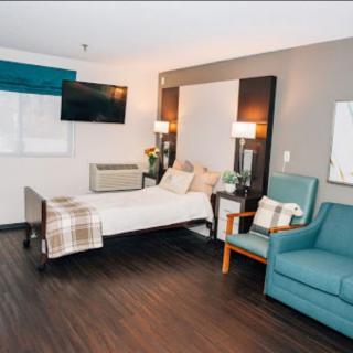 A modern and clean hospital room featuring a bed, television, and comfortable seating.