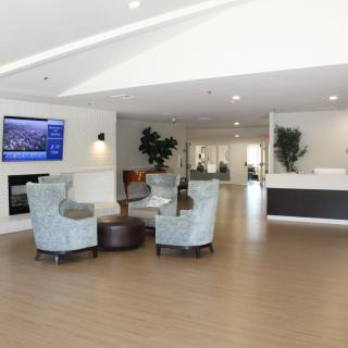 A modern lobby with comfortable seating, a reception desk, and a television.