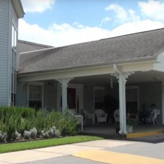 A residential building with a covered porch and well-maintained landscaping under a clear sky.