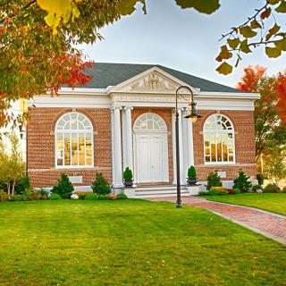 A quaint brick library building surrounded by autumn foliage.