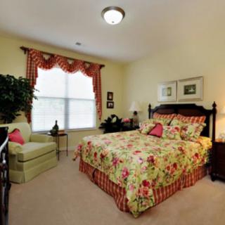 A cozy bedroom featuring floral bedding, an armchair by the window, and elegant decor.