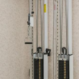 A close-up view of a cable machine with adjustable weights in a gym setting.