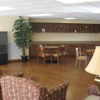 A cozy room with a television, tables, and chairs on a wooden floor.