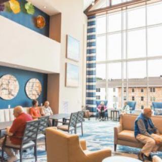 A modern lobby with comfortable seating and bright natural light, featuring artwork on the walls and large windows.