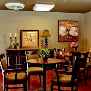 A cozy dining area with tables and chairs, decorated with artwork and plants.