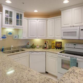 A modern kitchen with white cabinets and granite countertops.