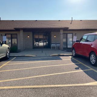 A view of a commercial building with parked cars in the foreground.