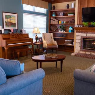 A cozy living room featuring a piano, fireplace, and comfortable seating.
