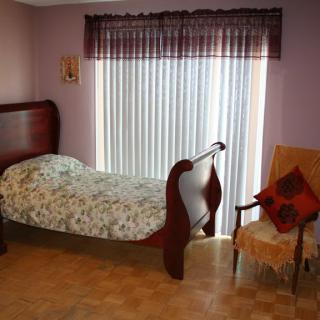A cozy bedroom with a single bed, chair, and window curtains.