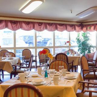 A well-lit dining room with set tables and comfortable seating.