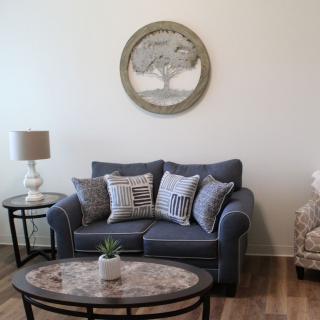 A cozy living room setup with a blue sofa and decorative pillows, accompanied by a coffee table and wall art.