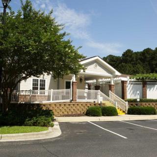 A small building with a parking lot and surrounding trees on a sunny day.