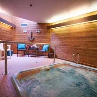 A serene indoor spa area featuring a jacuzzi surrounded by wooden walls and comfortable seating.