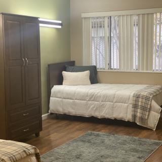 A tidy bedroom with a single bed, wardrobe, and window.